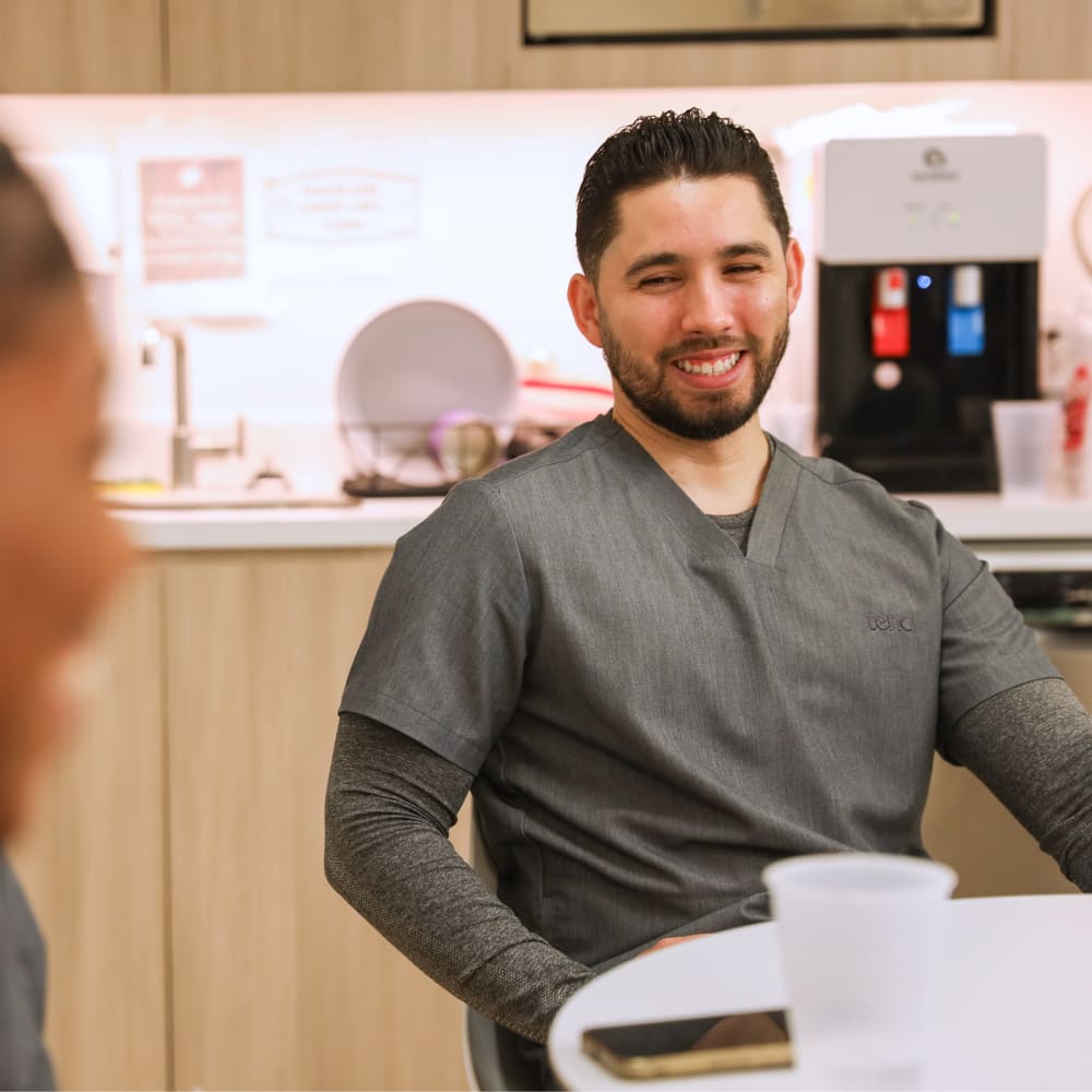 A Tend employee is in scrubs and is smiling.