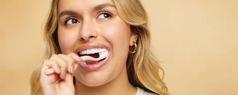 Smiling woman brushing her teeth.