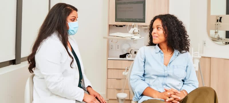 Woman in treatment chair speaking with dentist.